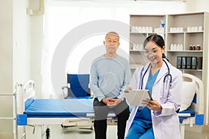 A nurse in charge takes care of a senior man to sleep in a room at the hospital department. Asian female doctor talking