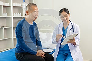 A nurse in charge takes care of a senior man to sleep in a room at the hospital department. Asian female doctor talking