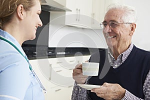 Nurse Chatting With Senior Man During Home Visit