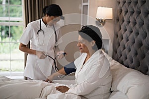 Nurse checking blood pressure of patient resting on bed photo