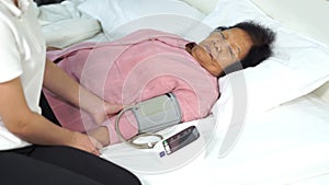 Nurse checking blood pressure of a senior woman on bed