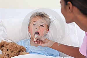 Nurse checking little boy throat in hospital