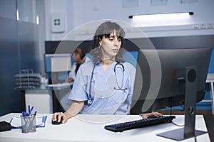 Nurse checking medical files on desktop