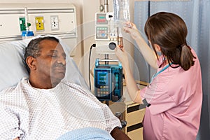 Nurse Checking Senior Patient's IV Drip On Ward photo