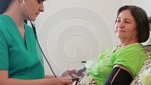 Nurse checking senior woman blood pressure