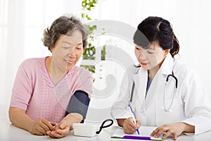 Nurse checking senior woman blood pressure
