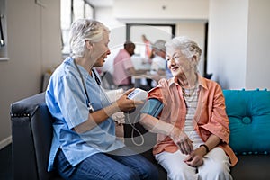 Nurse checking senior woman blood pressure at nursing home