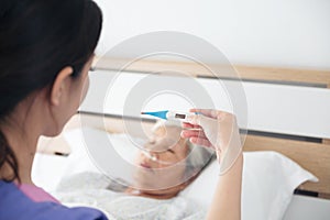 Nurse checking sick patient`s body temperature - fever. old asia