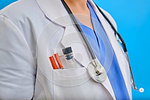 Nurse clothing with syringes and flask in the pocket, close-up. The body of a female doctor with a stethoscope in uniform