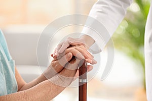 Nurse comforting elderly woman with cane against blurred background. Assisting senior generation photo