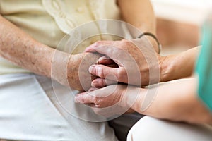 Nurse consoling her elderly patient by holding her hands