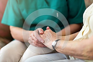 Nurse consoling her elderly patient by holding her hands