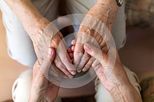 Nurse consoling her elderly patient by holding her hands