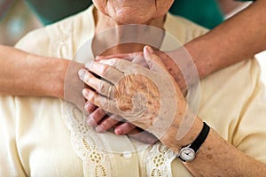 Nurse consoling her elderly patient by holding her hands