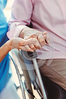 Nurse consoling a senior woman in the nursing home holding her hand