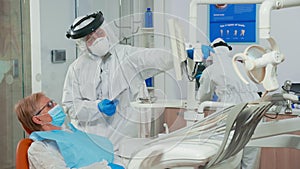 Nurse in coverall helping doctor with dental x-ray