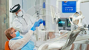 Nurse in coverall helping doctor with dental x-ray