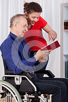 Nurse and disabled man reading book