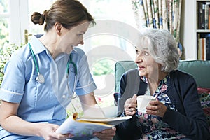 Nurse Discussing Medical Notes With Senior Woman At Home photo