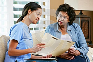 Nurse Discussing Records With Senior Female Patient During Home photo