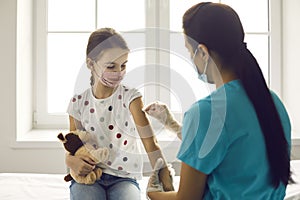 Nurse disinfects skin on child& x27;s arm before giving Covid-19 or flu vaccine injection