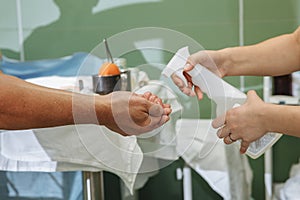 A nurse disinfects the surgeon`s hands with an antiseptic before the operation.