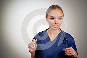 Nurse Doctor in blue uniform standing and looking away, holding stethoscope by both hands white background