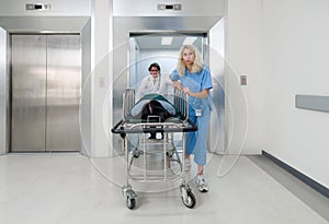 A nurse and doctor in propels a wheeled stretcher, carrying a patient out of the elevator to the emergency room of the hospital