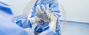 Nurse or doctor put surgical glove on surgeon \'s hand inside operating room in hospital.