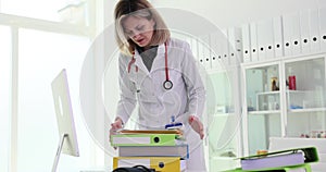 Nurse doctor with stack of documents files at workplace in clinic