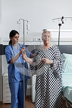 Nurse dressed with scrubs helping senior woman patient