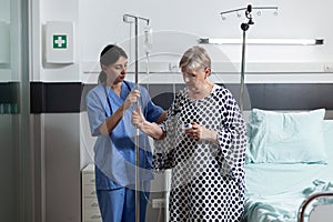 Nurse dressed with scrubs helping senior woman patient