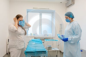 A nurse dresses a surgeon in a sterile suit before surgery