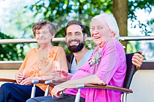 Nurse drinking coffee with seniors on terrace