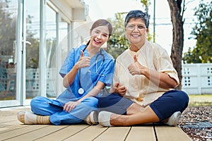 Nurse with elderly patient showing thumbs up showing health improvement from treatment outdoors.Health care concept