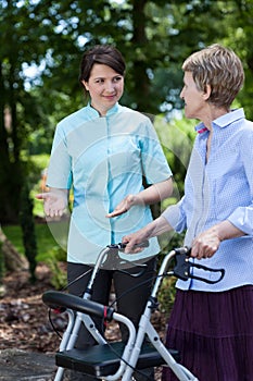 Nurse encourages older woman for walking photo