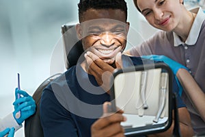 Nurse encouraging male client who looking at his teeth and smiling