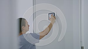 Nurse enters password on electronic smart monitor hanging on wall