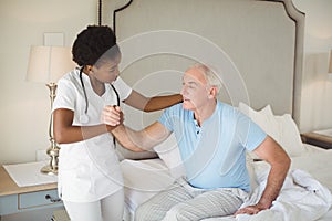 Nurse examining a senior man on bed in bedroom