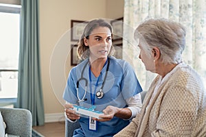 Nurse explaining medicine dosage to senior woman at nursing home