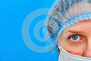A nurse with facial wounds in a medical mask, copy space. Doctor on a blue background with red marks from a protective mask