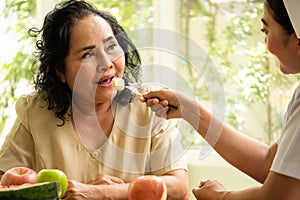 Nurse giving apple to adult female patient in the room
