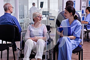 Nurse filing documents while talking with disabled senior woman