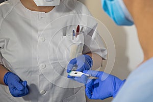 Nurse gives thermometer to another nurse