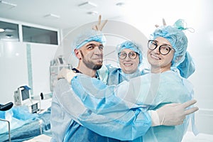 Nurse giving bunny ears to two colleagues in medical room