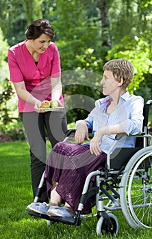 Nurse giving fresh fruits to elderly woman