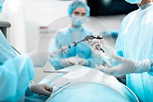 Nurse giving laparoscopic instrument to doctor during surgical operation photo