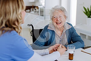 Nurse giving medicine to senior woman at her home.