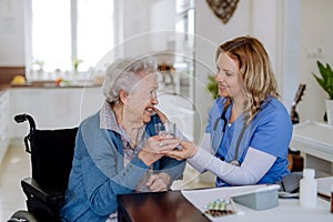 Nurse giving medicine to senior woman at her home.