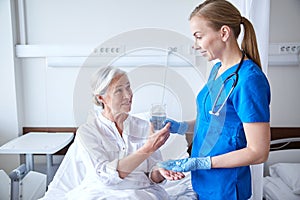 Nurse giving medicine to senior woman at hospital